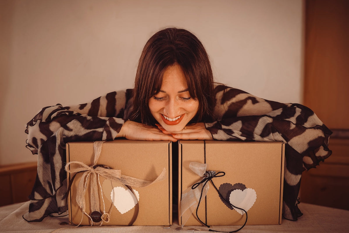 Tamara von Cacao Rituals lächelt über zwei verpackten Geschenkboxen